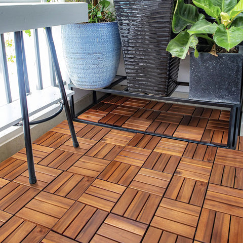 Teak Interlocking Patio Deck Tiles Set of 10 12 Inch by 12 Inch Outdoor Wood Flooring Mats on balcony with plants and table.