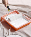 Hand using paint roller in 9 Inch Paint Tray Liners 20 Pack Disposable Plastic Trays for Roller Trays Fits Most Mini Paint Pans