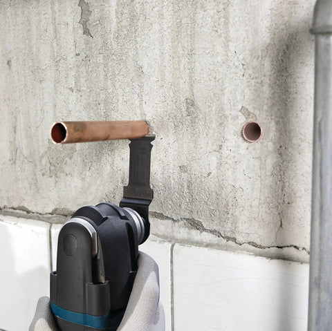 5 Piece Starlock Oscillating Multi Tool Blade Set cutting metal pipe in wall, showcasing plunge blade use for metal.