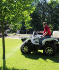 Person using 9 Gallon UTV And ATV Spot Sprayer with Everflo 1.0 GPM pump, spraying tree from a vehicle in a grassy area