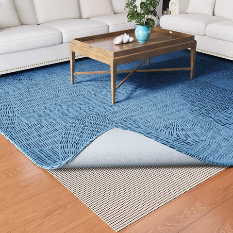 Heavy Duty Non Slip Rug Pad Gripper 2x3 Feet for Area Rugs shown under a blue carpet on hardwood floor in a living room.