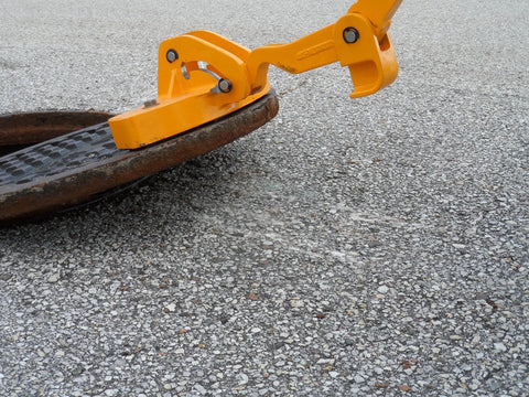 Kickass Three Magnet Manhole Lid Lifter Pulls Up To Two Hundred Fifty Pounds No Sweat, lifting a manhole cover with yellow handle.