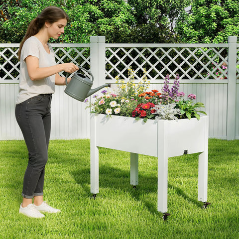 Woman watering an Elevated Raised Garden Bed With Wheels Portable Resin Planter Box For Vegetables Flowers And Herbs Outdoor Weather Resistant White Ready To Roll On The Patio Or Balcony Easy To Move