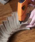 Person using glue gun with Weatherproof Hot Glue Sticks 4 Inches Long By 0.43 Inches Diameter on burlap fabric for crafting.