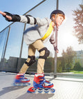 Child skating on pavement wearing LED Light Up Inline Skates For Kids With Three Adjustable Sizes, helmet, knee pads, and elbow pads.