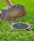 Person placing Massive Dope Decorative Outdoor Faux Stone Rock With Realistic Sandstone Look over a utility cover