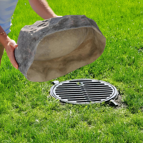 Person placing Massive Dope Decorative Outdoor Faux Stone Rock With Realistic Sandstone Look over a utility cover