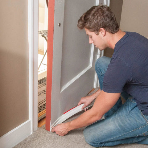 Man installing All In One Door Seal Kit With Weather Strips For Doors And Windows White Includes 39 Ft Self Adhesive Weather Strips.