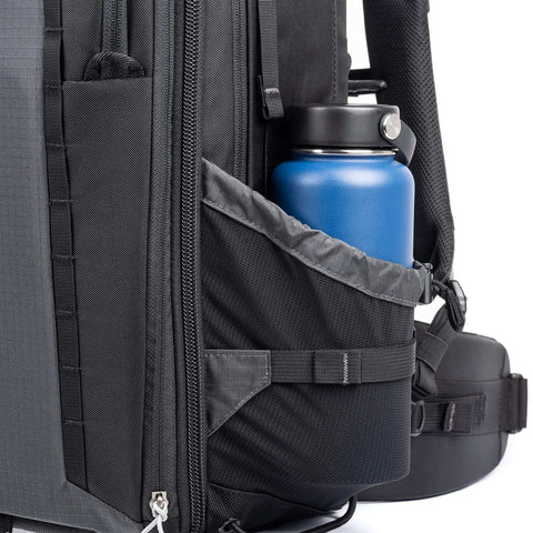 Side view of 46L Camera Backpack For Travel Photography With Expandable Front Pocket holding a blue bottle