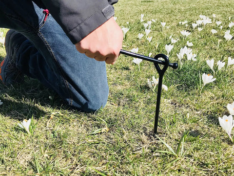 Person using 8 Pack Ground Anchors Set 15 Inch Tall One Quarter Inch Diameter With 65 Feet Of Rope Beefy Heavy Duty Tie Down Stakes