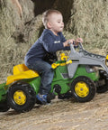 Child riding a green Pedal Tractor With Working Front Loader And Detachable Trailer For Kids Ages 3 And Up, outdoors in hay