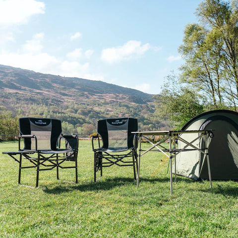 Heavy Duty Oversized Camping Directors Chair With Side Table And Built In Pocket for outdoor use, set on grass near tent
