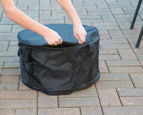 Person zipping Heininger Heavy-Duty Carry Bag For Portable Fire Pit - Vinyl Storage And Transport Case on patio