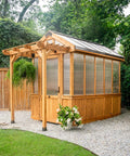 Outdoor view of Bellerose Walk In Greenhouse Kit with cedar wood frame, polycarbonate panels, and pergola cover.