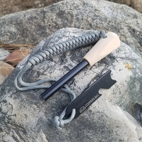 Ferro Rod Fire Starter Kit With A Large One Half Inch Rod, Fire Tinder And Custom Carry Pouch, All In One Survival Fire Starting Tool Package For Backcountry Camps And Emergencies In Green displayed on a rock