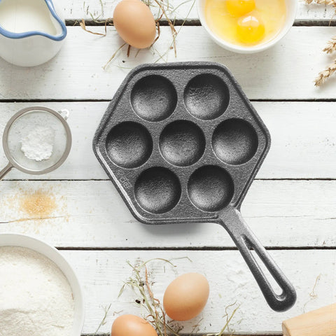 Seven Section Cast Iron Danish Aebleskiver Pan For Mini Puffs And Pancake Balls Preseasoned Heats Evenly On All Cooktops Including Induction Grill Ready Outdoor Kitchen Gadget For Busy Breakfasts And Weekend Brunch, surrounded by baking ingredients.