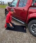 Person kneeling on VersaMat Roll Up Workhorse High Density Foam Utility Mat Black For Garage And Home 1 Inch Thick Closed Cell Foam