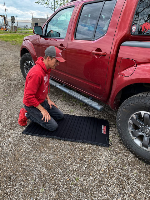 Person kneeling on VersaMat Roll Up Workhorse High Density Foam Utility Mat Black For Garage And Home 1 Inch Thick Closed Cell Foam
