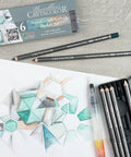 Water-Soluble Graphite Pencils Set With Aquarelle Finish, Six HB Pencils In White, Brown, Teal, Green, Red, And Blue For Dope Washable Sketching And Watercolor Effects shown with geometric sketch and packaging.