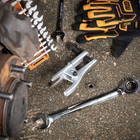 GearWrench ball joint separator 3916D, silver fork tool on asphalt with gloves and wrench nearby