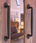 Front view of Two Pack 12 Inch Diamond Tapered Barn Door Handles Black Cast Iron Pulls installed on wooden sliding doors indoors