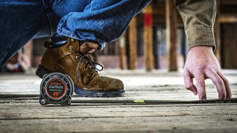 Worker using 1-3/16 Inch By 25 Foot Dual Sided Tape Measure With Nite Eye Glow, Shockforce Blade And Matte Black Nylon Coated Blade