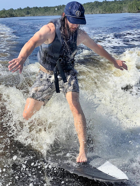 Person wakesurfing on Mondo 5 Foot 2 Inch Wakesurf Board With EVA Padding Thruster Fin Design on a sunny day