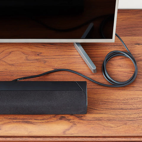 Built Tough Toslink Optical Audio Cable 6 Foot Premium Gold Plated Connectors plugged into soundbar near TV on wooden surface.
