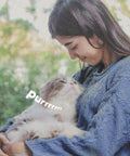 Woman smiling at a fluffy cat in her arms with text 'purrrrrrr' on the image.