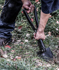 Person using 18 Inch Military Folding Camping Shovel for Offroad Survival Olive Green High Carbon Steel Entrenching Tool in grass.