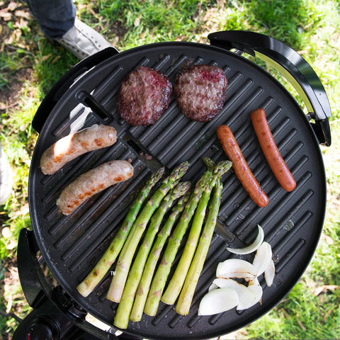 Top view of Go To Indoor Outdoor Electric Patio Grill With Removable Stand grilling sausages, burgers, asparagus, and onions.