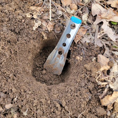 Ultralight Backpacking Trowel 0.48 Oz 13.5 G Blue With Lifetime Warranty Made In USA digging in soil outdoors.
