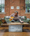 Man using iD4 MkII Audio Interface With Class A Mic Preamps, USB C on coffee table, playing guitar in loft studio, brick wall background