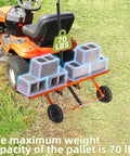 40 Inch Orange Tow Behind Dethatcher With 24 Spring Steel Tines For Removing Thatch Leaves And Needles From Large Lawns Heavy Duty Pull Behind Lawn Rake attached to a lawn tractor with cinder blocks on top to show weight capacity.