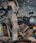 Mechanic using Pinless Universal Joint For Impact Sockets Three Eighths Inch Drive X Core Design Delivers Four Times The Durability Ball Detent Keeps Sockets Locked In 30 Degree Flex For Tight Angles Heavy Duty Tool Accessory Built For Pros on a car suspension.