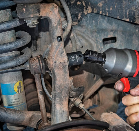 Mechanic using Pinless Universal Joint For Impact Sockets Three Eighths Inch Drive X Core Design Delivers Four Times The Durability Ball Detent Keeps Sockets Locked In 30 Degree Flex For Tight Angles Heavy Duty Tool Accessory Built For Pros on a car suspension.