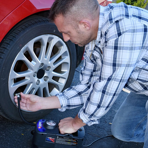Man using Portable 150 PSI Air Compressor For Cars Trucks And Bikes With 120V Power Built In Gauge Presta Adapter Inflator Needle to inflate tire