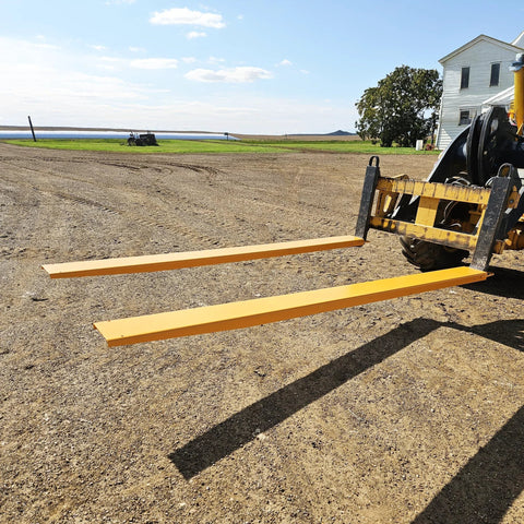 Pair of 92-inch forklift pallet fork extensions, 4-inch wide, yellow steel, attached to a forklift.
