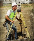 Professional Grade High Visibility Safety Vest Class 2 Reflective Trim Heavy Duty Construction Workwear For Outdoor Crews Safety Green Medium worn by a worker using surveying equipment on a construction site.