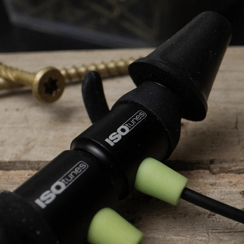 Close-up of All Day Wireless Hearing Protection Earbuds With 26 dB NRR, Passive Noise Isolation, black and green design, on wood.