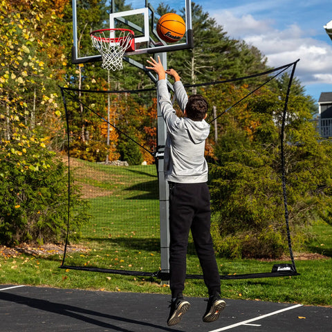 Man shooting basketball with XL Defender Pro Basketball Rebounder Net For Outdoor Driveway Hoops, Quick Setup Easy Fold Design.
