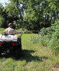 Man using 15 Gallon ATV Boomless Broadcast Sprayer With 16 Foot Swath, 2.2 GPM On Demand Diaphragm Pump near trees