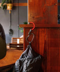 HeroClip Carabiner Gear Clip And Hook Medium holding bag on wood post in cafe environment.