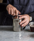 Handheld Milk Frother For Creamy Foam In Seconds, On The Go Stainless Steel Foamer used on a counter with coffee and milk