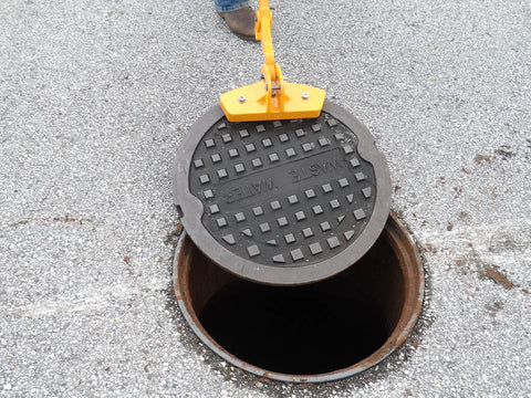 Kickass Three Magnet Manhole Lid Lifter Pulls Up To Two Hundred Fifty Pounds No Sweat Featuring Boss Level Neodymium Magnets And Ergonomic Handles For Fast Pro Worker Repairs Made In Usa lifting a manhole cover with a secure grip.