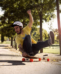 Skateboarder performing a slide with Stimulus 70mm 86A Freeride Longboard Wheels Yellow Set of 4 in a sunlit park.