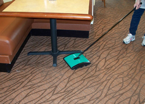 Heavy Duty Manual Rotary Floor Sweeper Featuring Dual Nylon Brush Rolls Seven Point Five Inch Path And Twin Catch Pans in use on carpet.