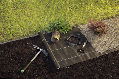 Heavy Duty Woven Weed Control Fabric 6 by 33 Feet Black Ground Cover Membrane on garden lawn for weed suppression.