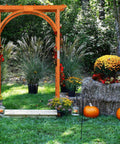 85 Inch Wooden Garden Arch Trellis For Climbing Plants in a lush garden with pumpkins and hay, natural brown wood finish