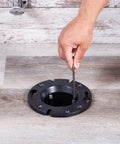 Hand installing 4-Inch ABS Cast Iron Closet Flange Replacement with Rubber Gasket and Stainless Steel Bolts on floor